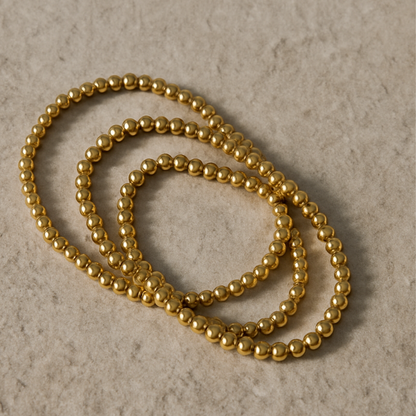 Gold beaded necklace on a textured beige background
