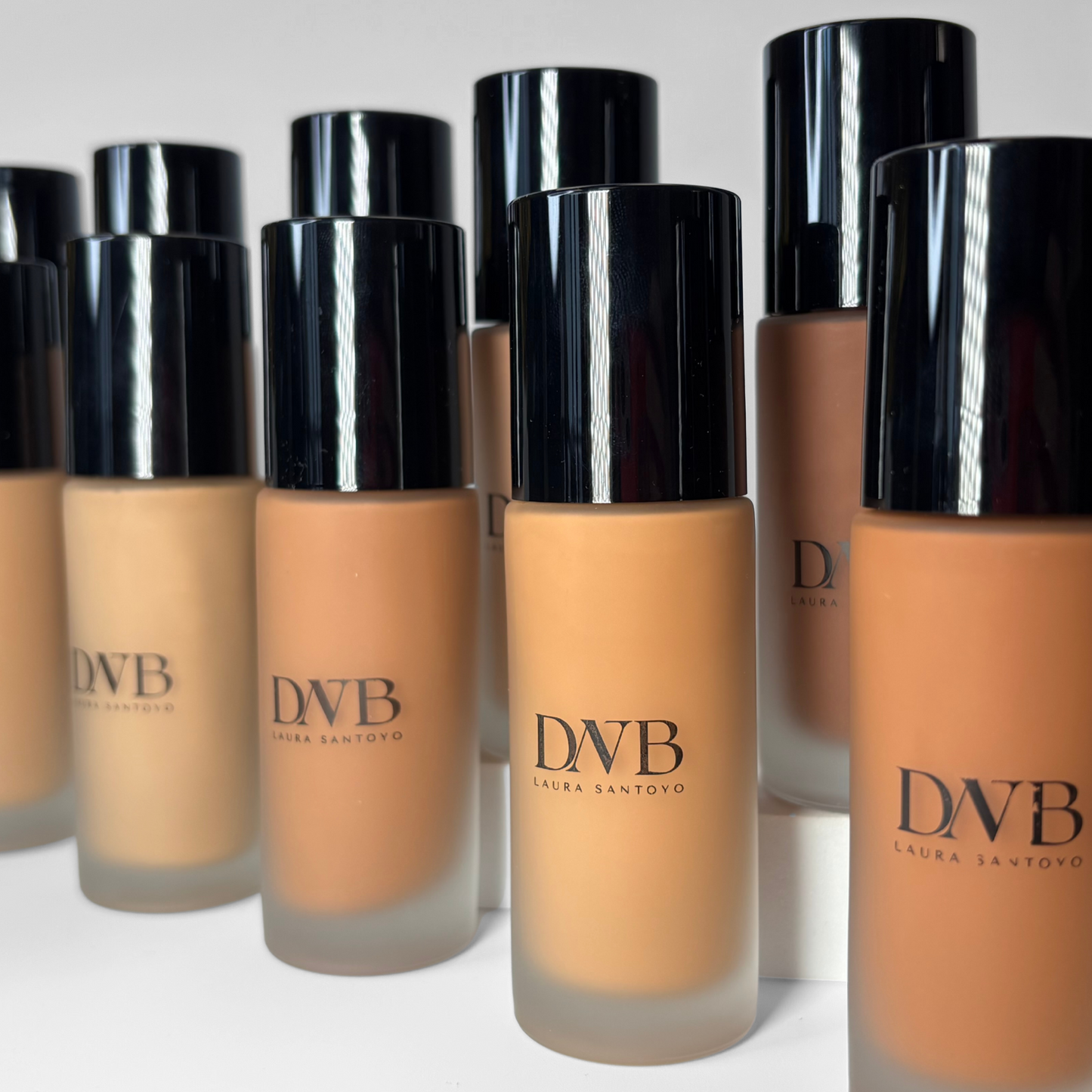 Row of DNB foundation bottles with black caps on a white background