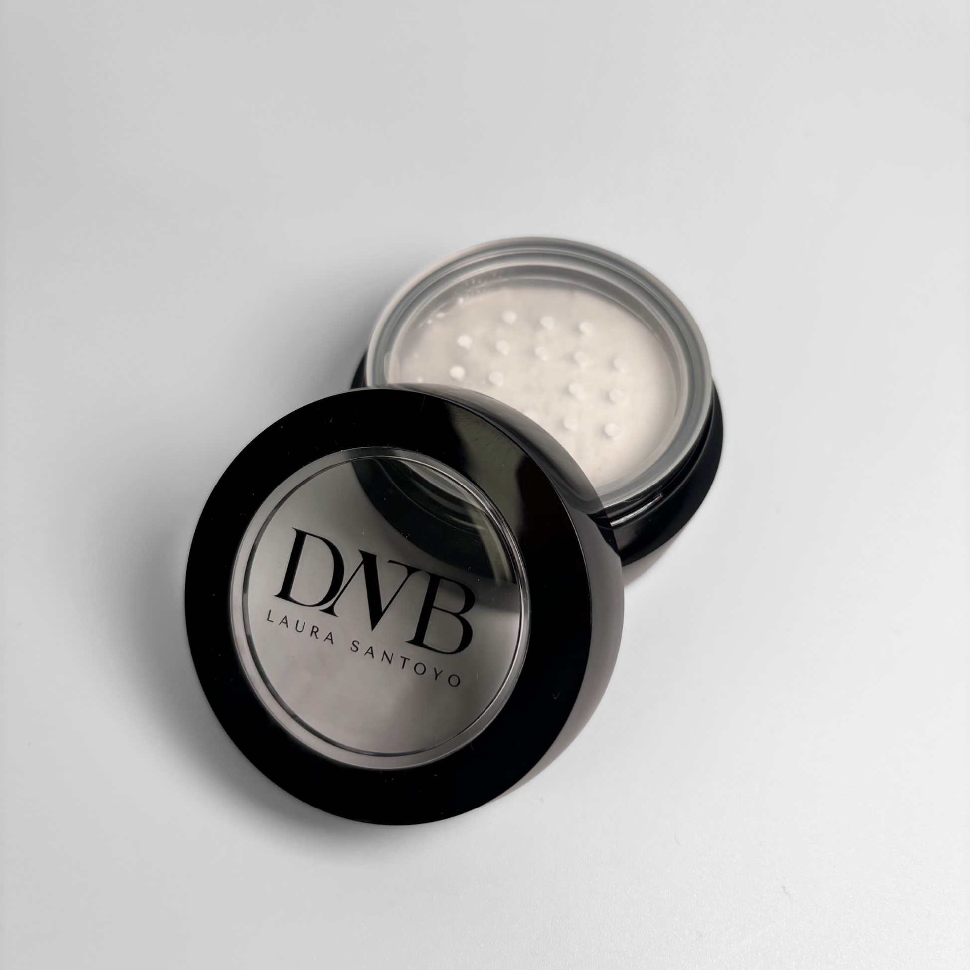 Black makeup compact with DNB branding on a light gray background