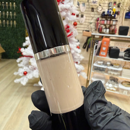 Cosmetic bottle held by a gloved hand with a blurred store background